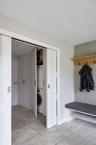 A small utility room containing laundry appliances hidden behind white sliding doors