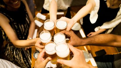 A group of people "cheers" each other with glasses of beer.