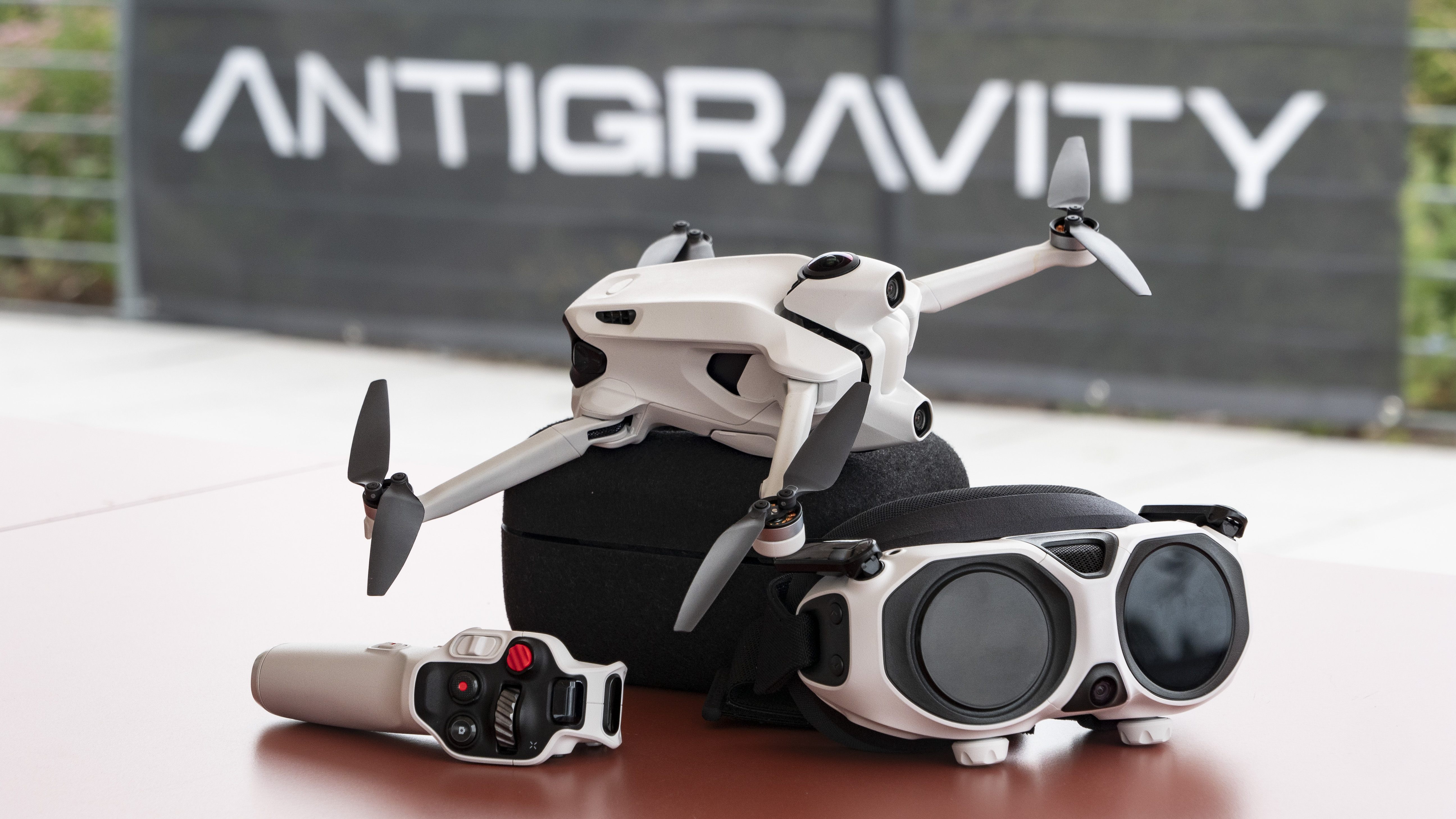 Antigravity A1 drone by Insta360 alongside its headset and controller, on a red table