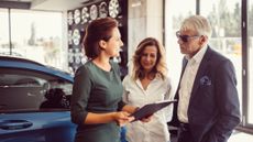 Buying a car. An older couple meets with a car salesman in the showroom. 