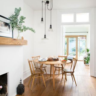White dining room with wooden floor, table and chairs and adjustable pendant lighting