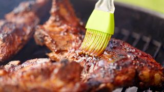 Basting meat on grill with brush