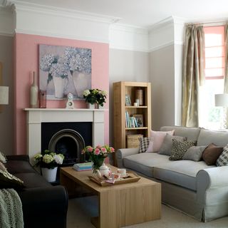 living room with cream and pink colour wall grey and black sofa wooden shelve and fireplace