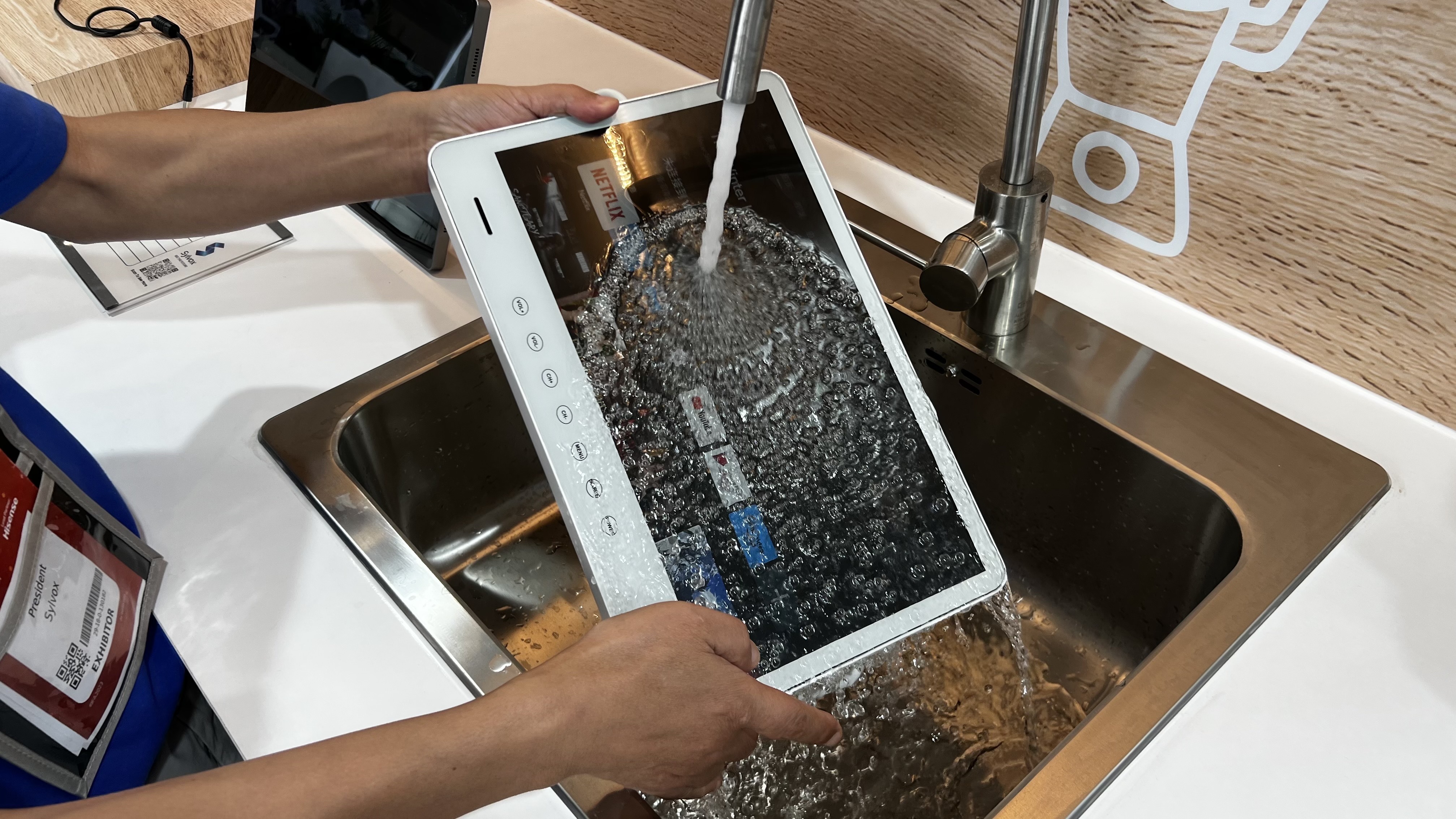 Two hands holding a waterproof TV in a sink