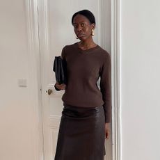 a woman wearing a brown v neck and brown leather skirt