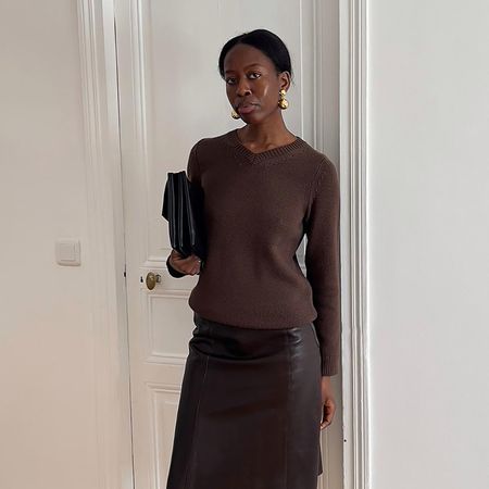 a woman wearing a brown v neck and brown leather skirt