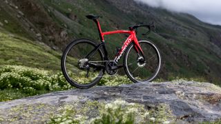 Red Pinarello F road bike standing on a rock in a mountain location