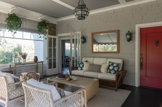 front porch seating space with basket chairs and sofa and hanging plants and red front door