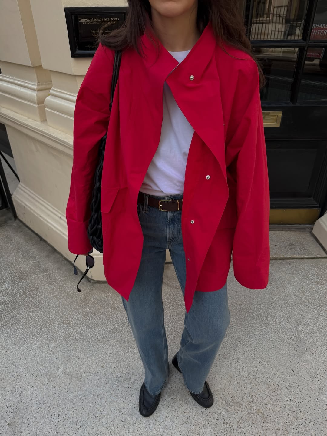 Influencer Francesca Saffari wearing a red funnel-neck jacket, straight jeans and loafers.