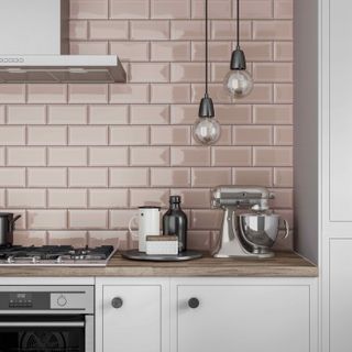 light pink glossy metro subway tiles in a white kitchen with wood countertop