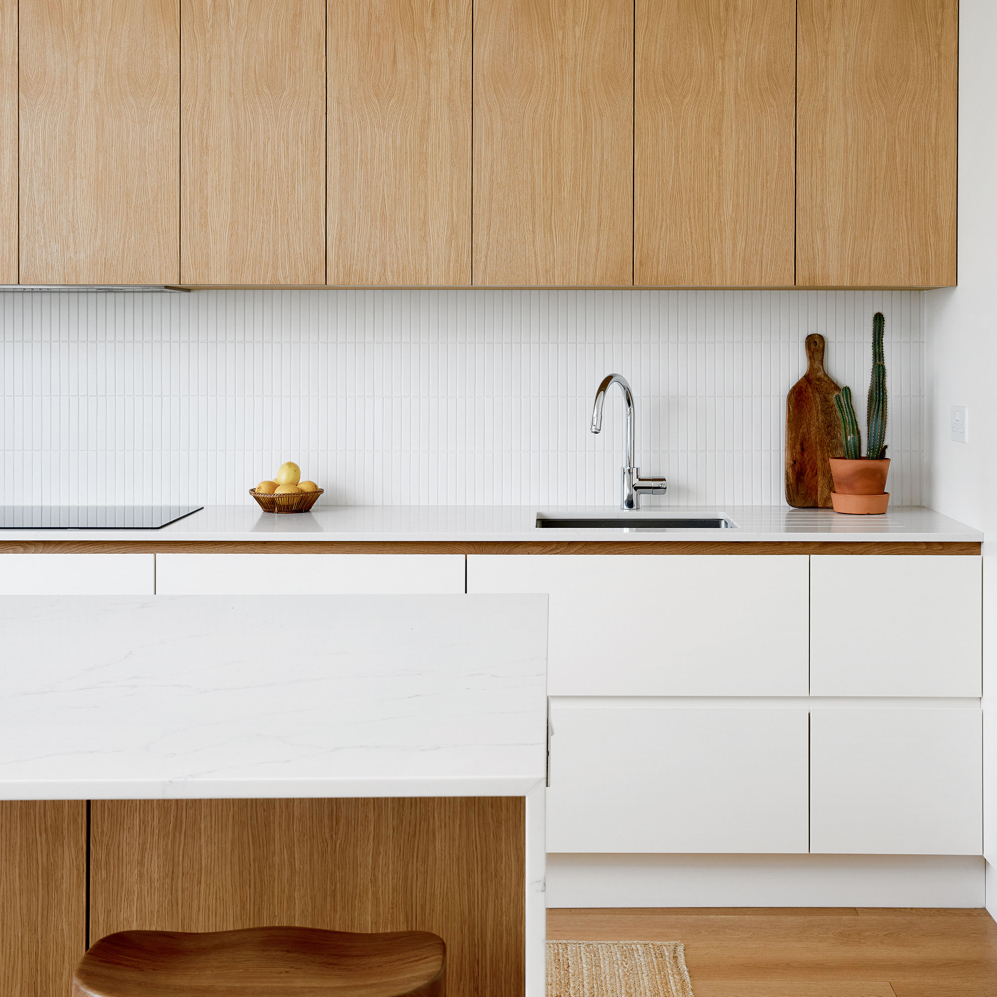White kitchen with light wooden details and white tiled splashback