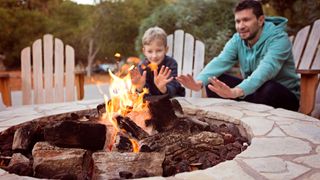 Father and son keeping warm by an outside firepit