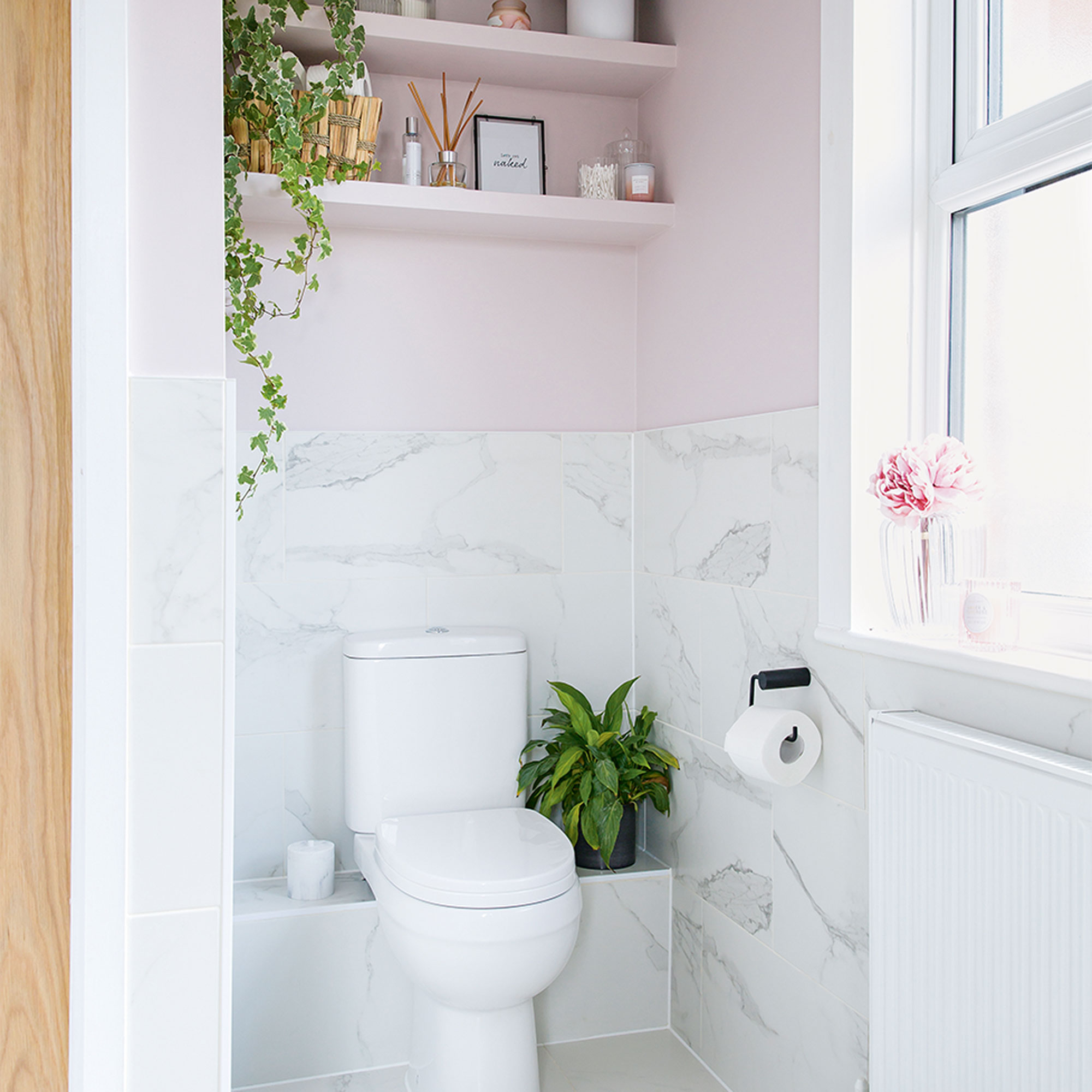 Pink bathroom with alcove and toilet with shelves above