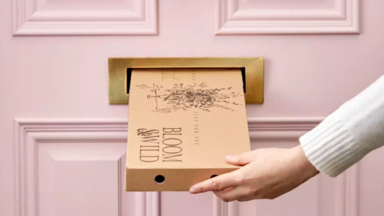 Best flower delivery UK: Bloom &amp; Wild letterbox flowers package being posted through pink door