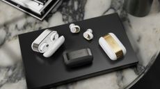 The Devialet Gemini II earbuds in all colours on a black and marble background