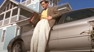 Jim Carrey being filmed leaning next to his car from a very low angle.