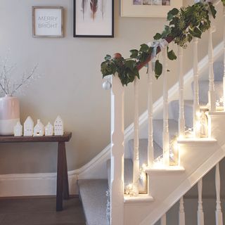 Christmas garland on white bannister in hallway.