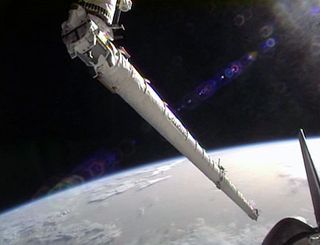 Space shuttle Endeavour's robotic arm reaches for the Orbiter Boom Sensor System.