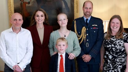 Kate Middleton posing with teenage photographer Liz, her brother, father, mother and Prince William standing in front of a painting of a horse