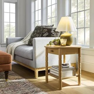 A gray sofa and wooden side table with a green and white table lamp