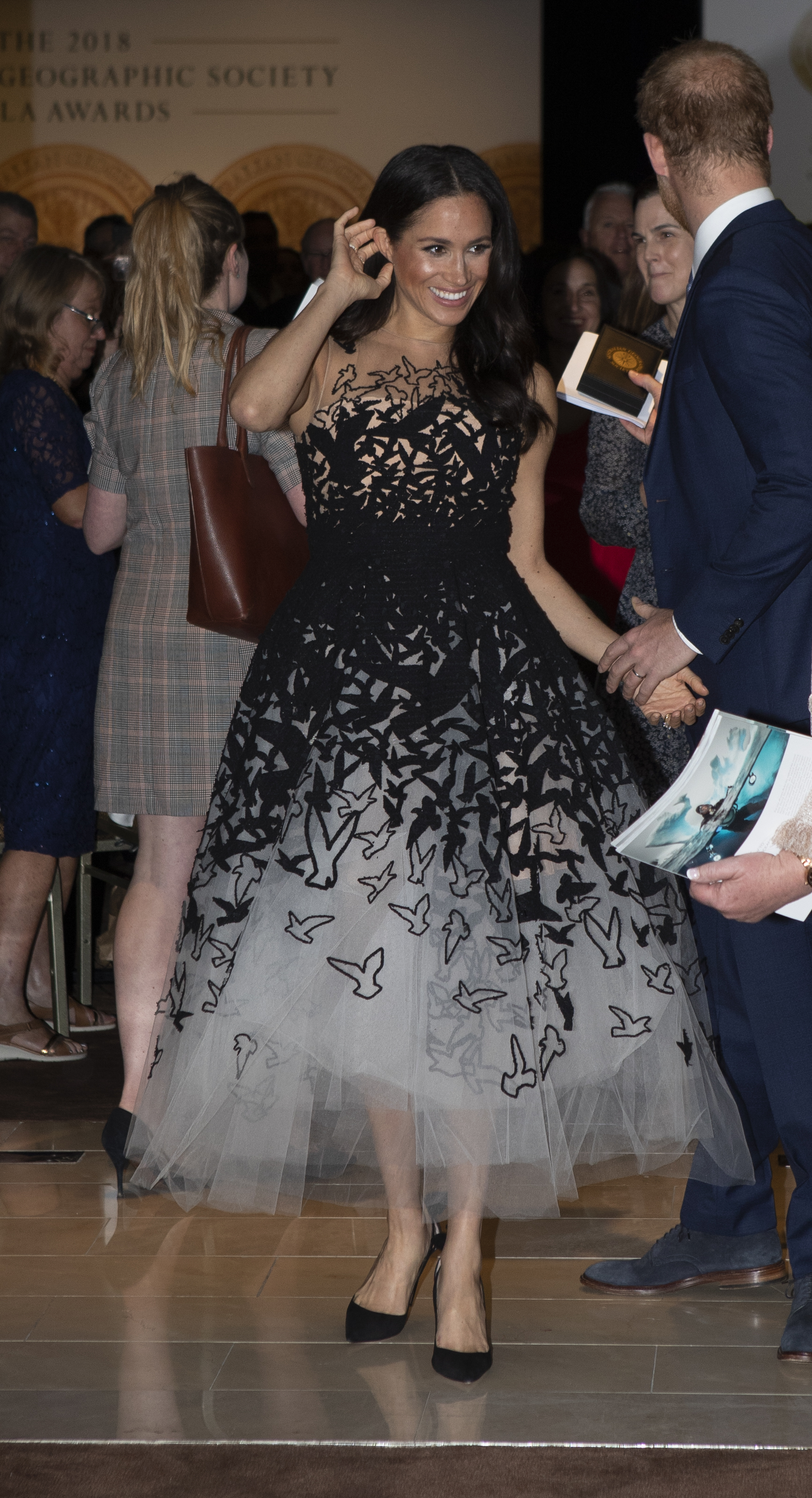 Meghan Markle wearing a black and white bird print dress and smiling