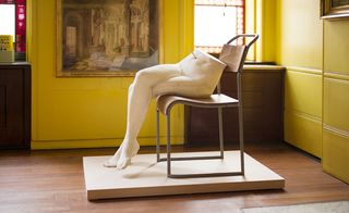 Female sculpture of crossed legs sitting on a chair