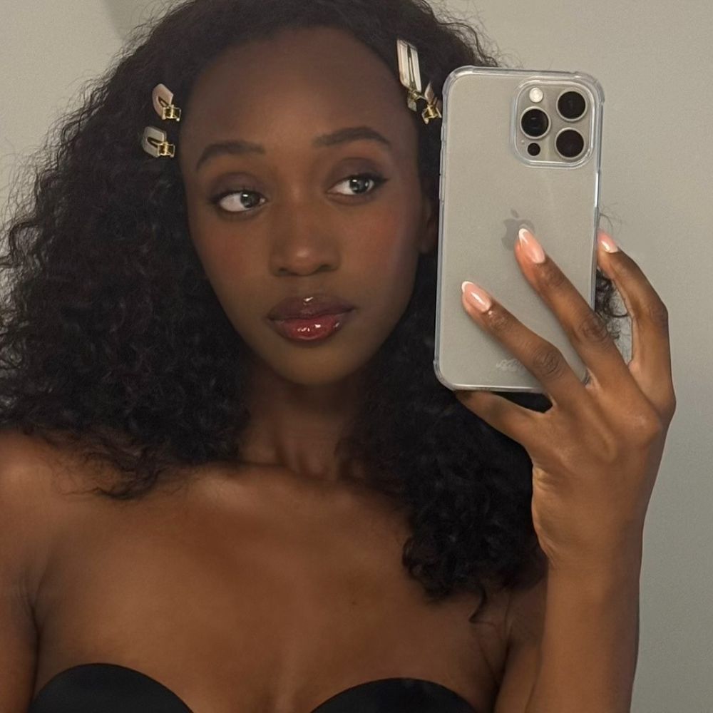 A woman with curly hair taking a selfie in a mirror