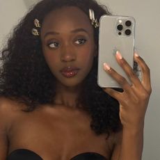 A woman with curly hair taking a selfie in a mirror