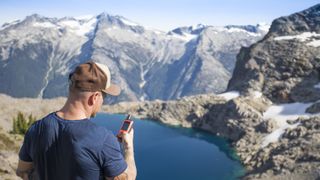 Man stood on a mountain and using a satellite communicator