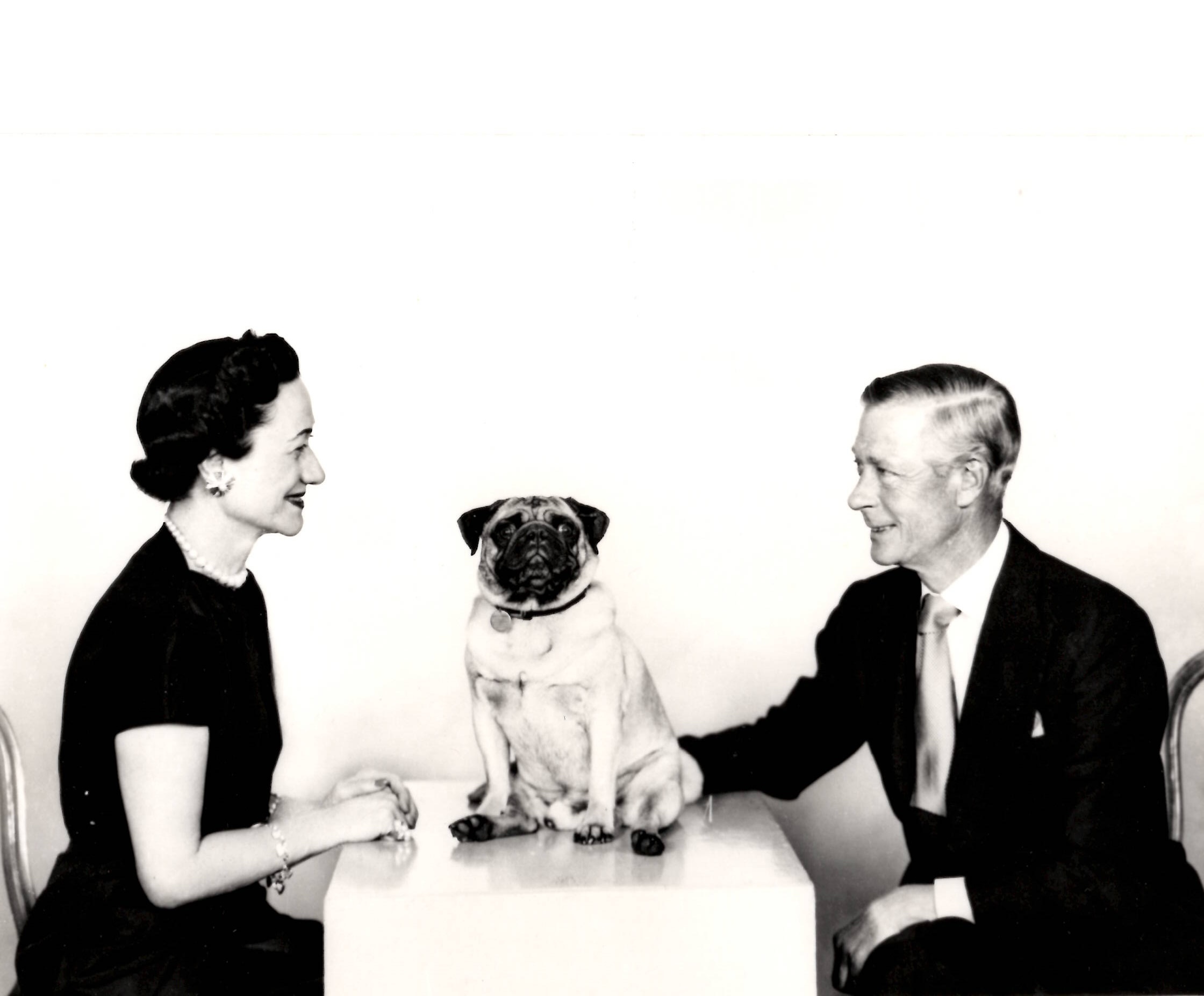 The Duchess and Duke of Windsor sitting opposite each other with a pug dog in the middle