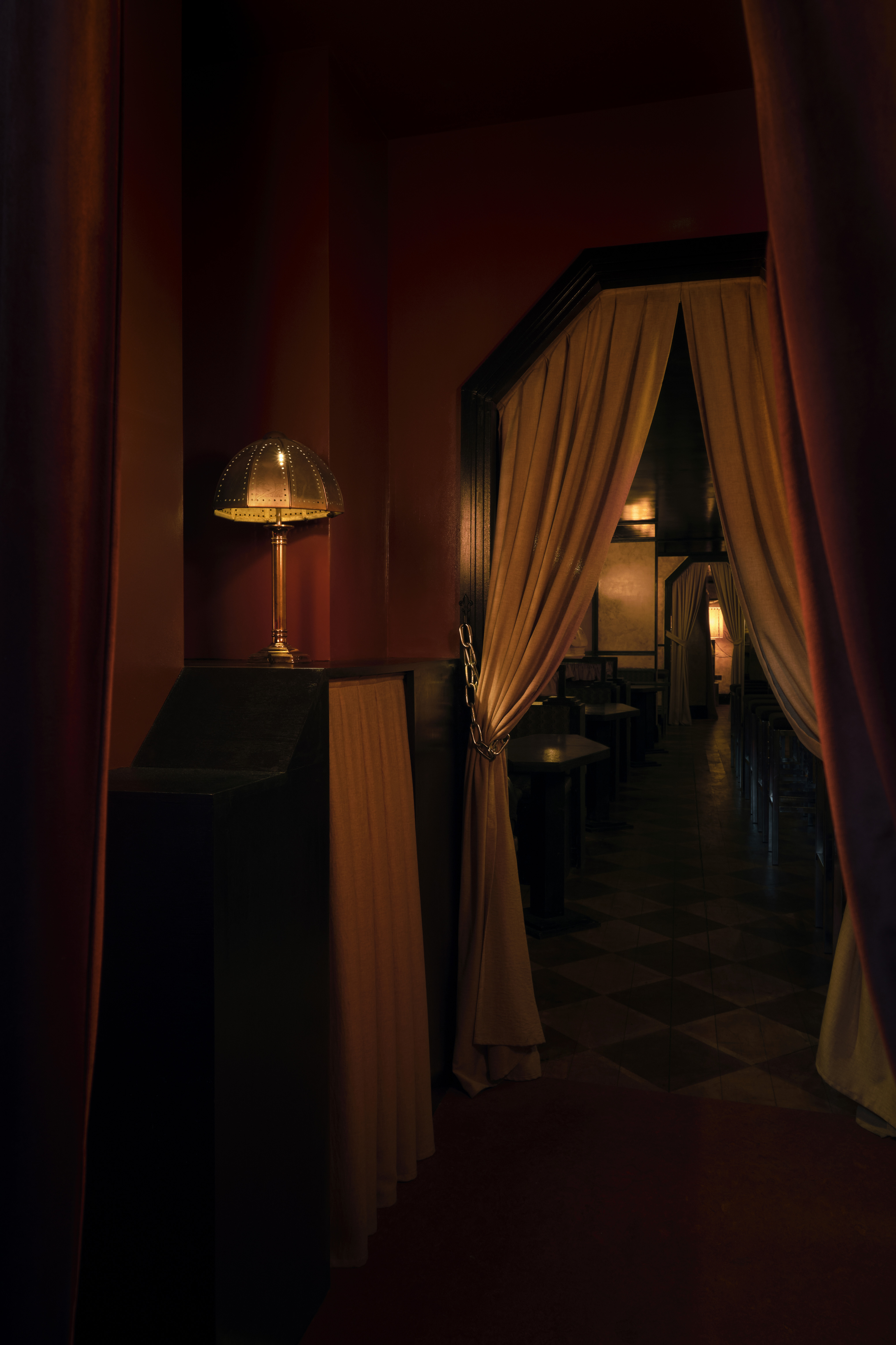A golden-hued, dimly lit nightclub features velvety red or ochre plush fabrics, reflective surfaces, Art Deco-inspired sconces, and an air of mystery.
