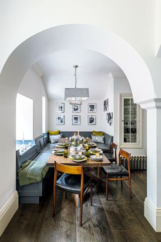 banquette seating around dining table with arched entrance