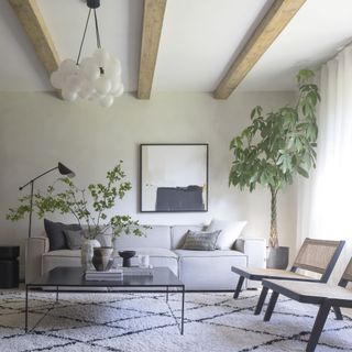 A white living room with faux wooden beams and minimalist furniture