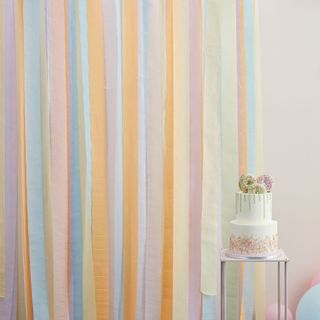 pastel pink wall with colourful fringed curtain and cake