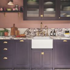 Kitchen with marble worktop and purple cabinets, and pink painted walls
