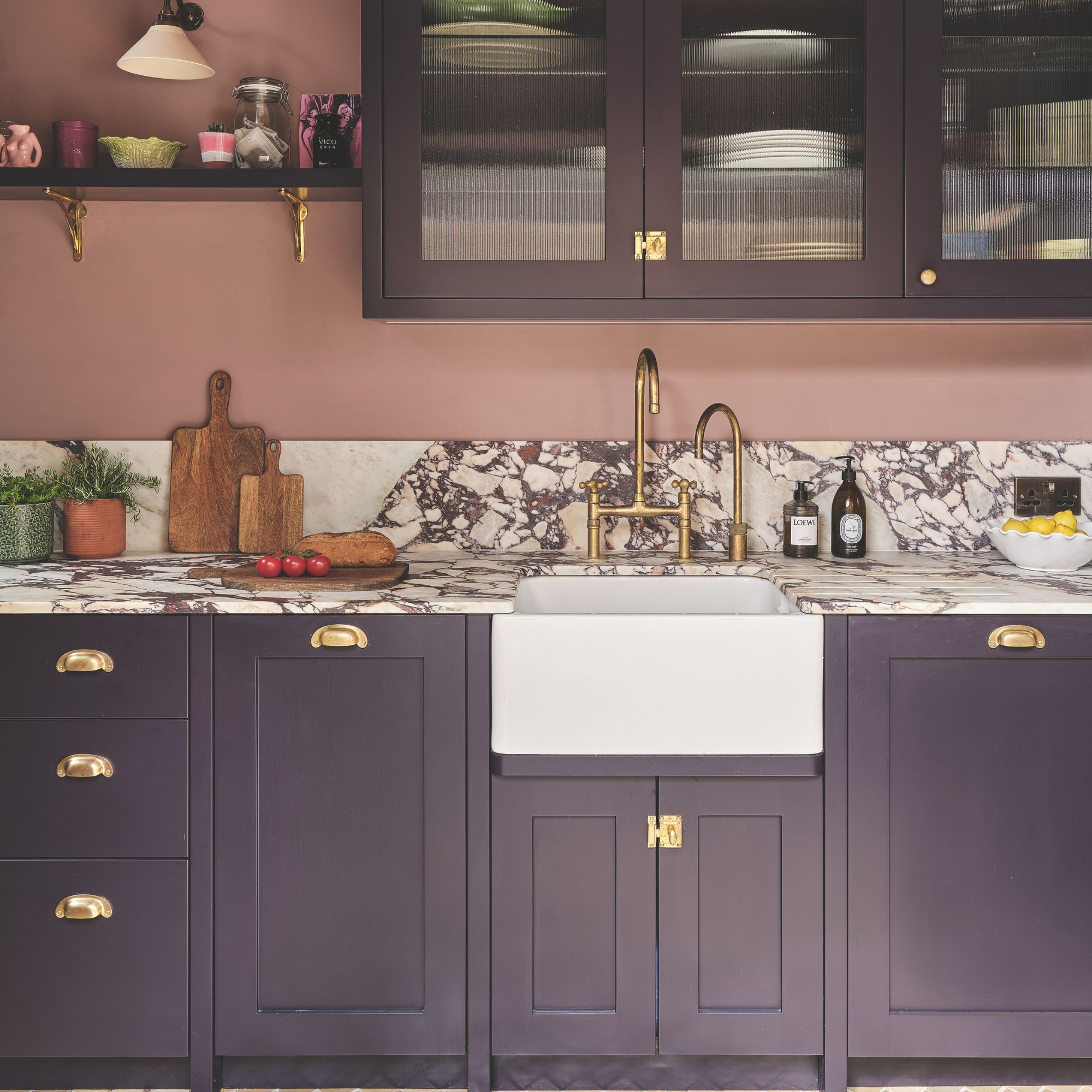 Kitchen with marble worktop and purple cabinets, and pink painted walls
