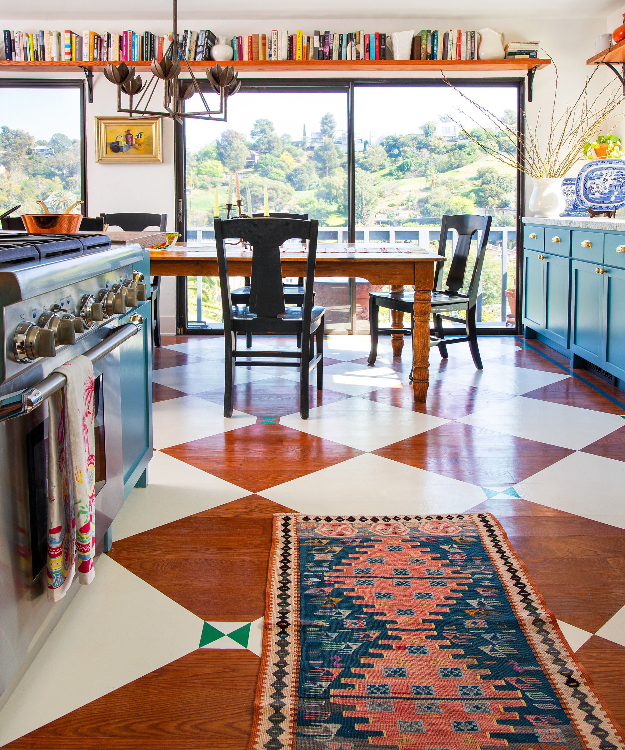 A blue kitchen with wooden flooring painted with a classic checkerboard pattern
