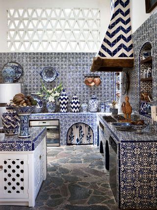 Stone floor, blue and white patterned tiled wall, surface tops and shelves