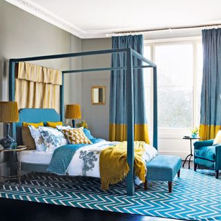 four poster bed in blue bedroom with large rug