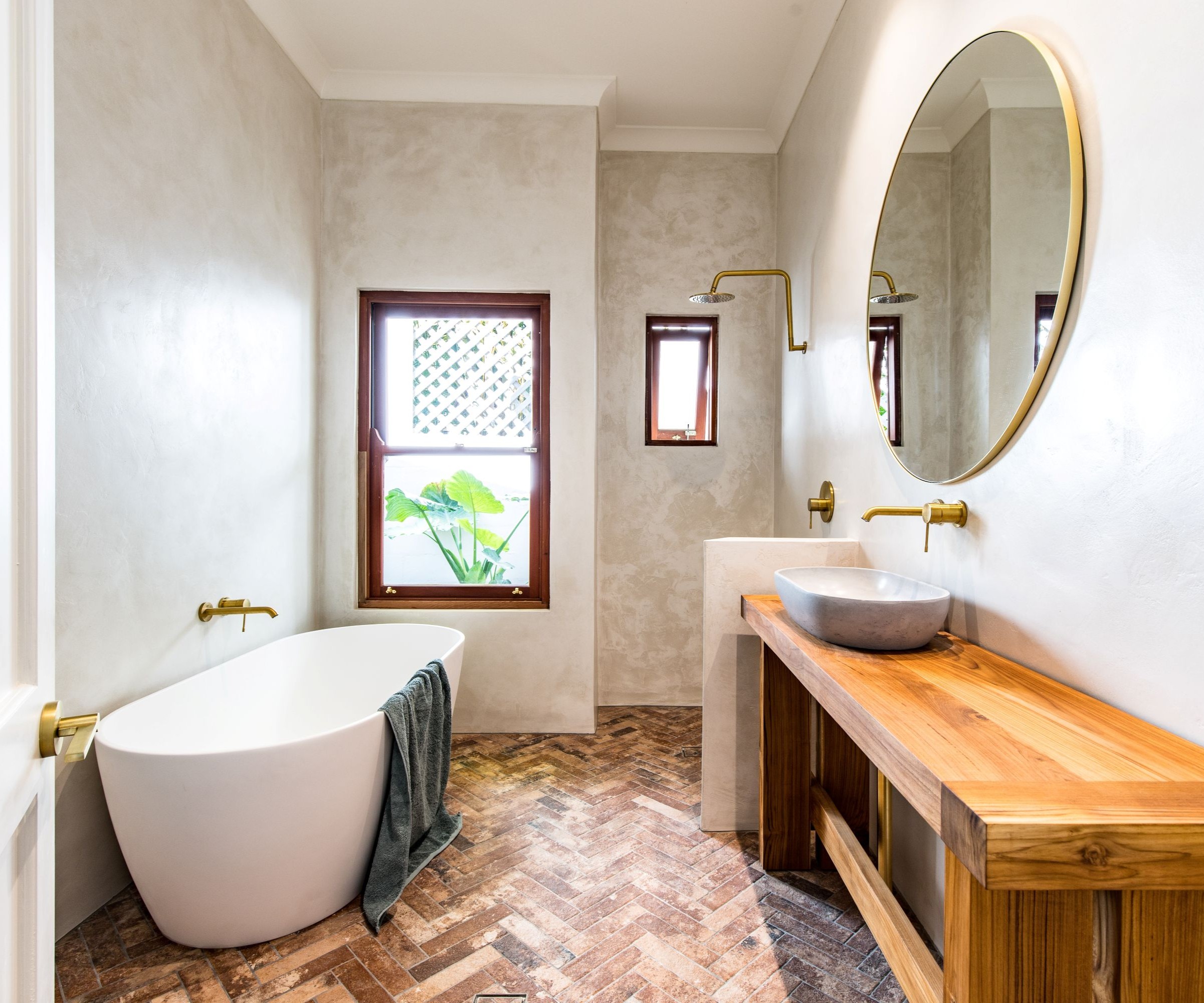 Grey plastered walls with a freestanding bathtub and a wooden washstand