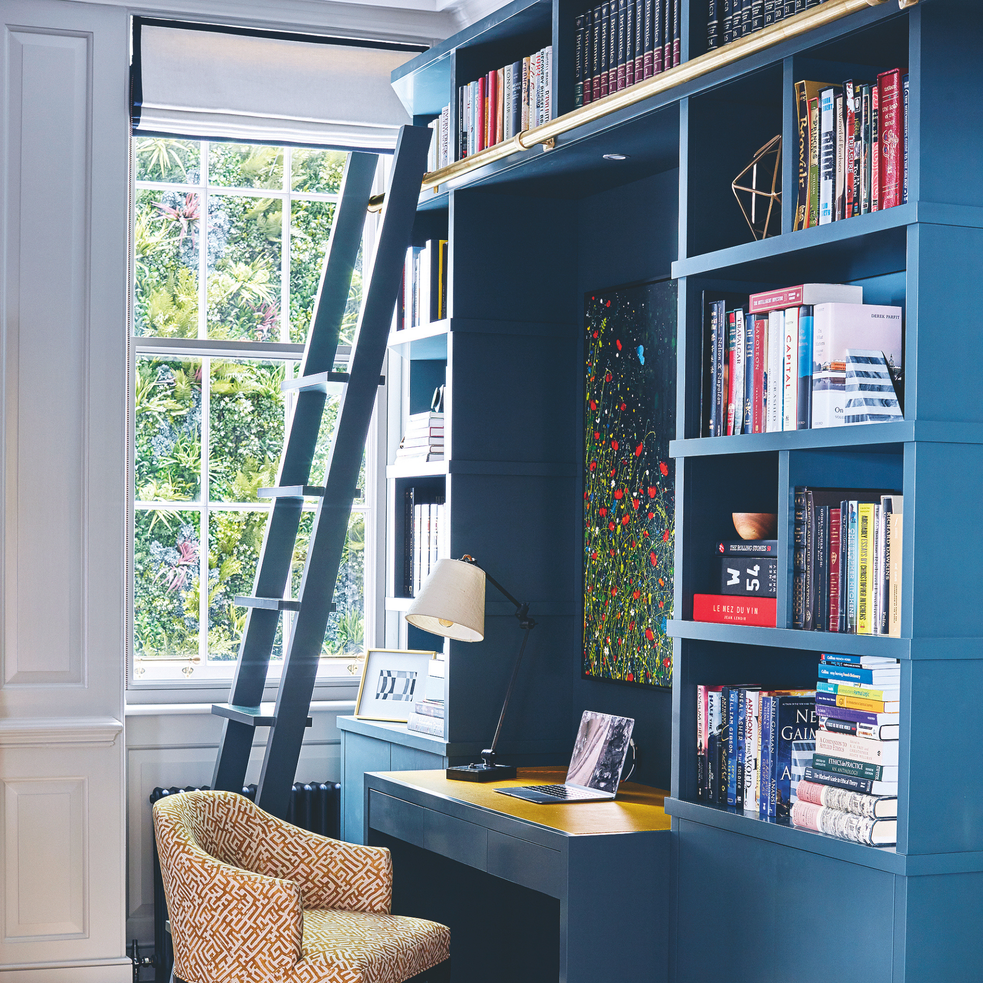 Built in desk and bookcase filled with books in a study with wooden floor and sash window. A restored Georgian Grade II listed townhouse converted from an office building in London.