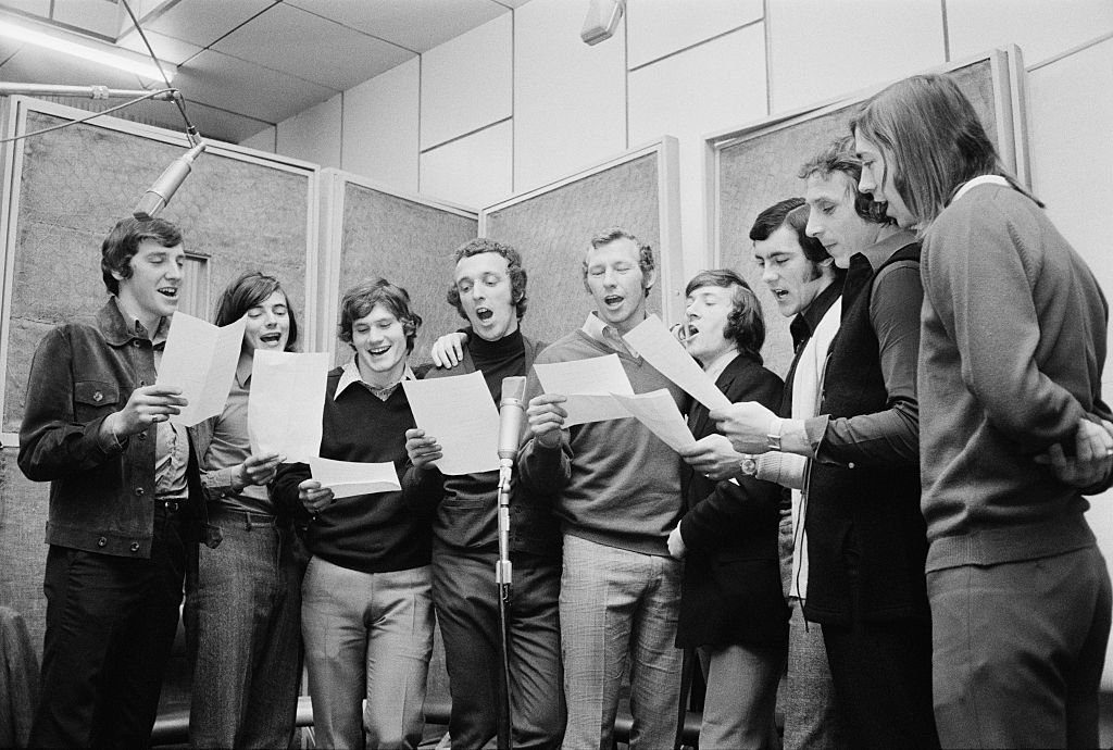 Arsenal footballers in a recording studio in London, UK, to record the single &#039;Good Old Arsenal&#039;, April 1971. They sang the song at the 1971 FA Cup Final in May. From left to right, Sammy Nelson, Peter Marinello, Pat Rice, Geoff Barnett, Bob Wilson, George Armstrong, Ray Kennedy, John Radford and Charlie George. (Photo by Les Lee/Daily Express/Getty Images)