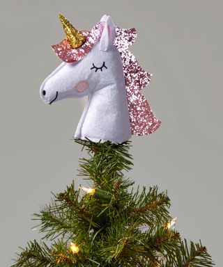 A white fabric unicorn head Christmas tree topper with blush mane and golden horn embellished with sequins