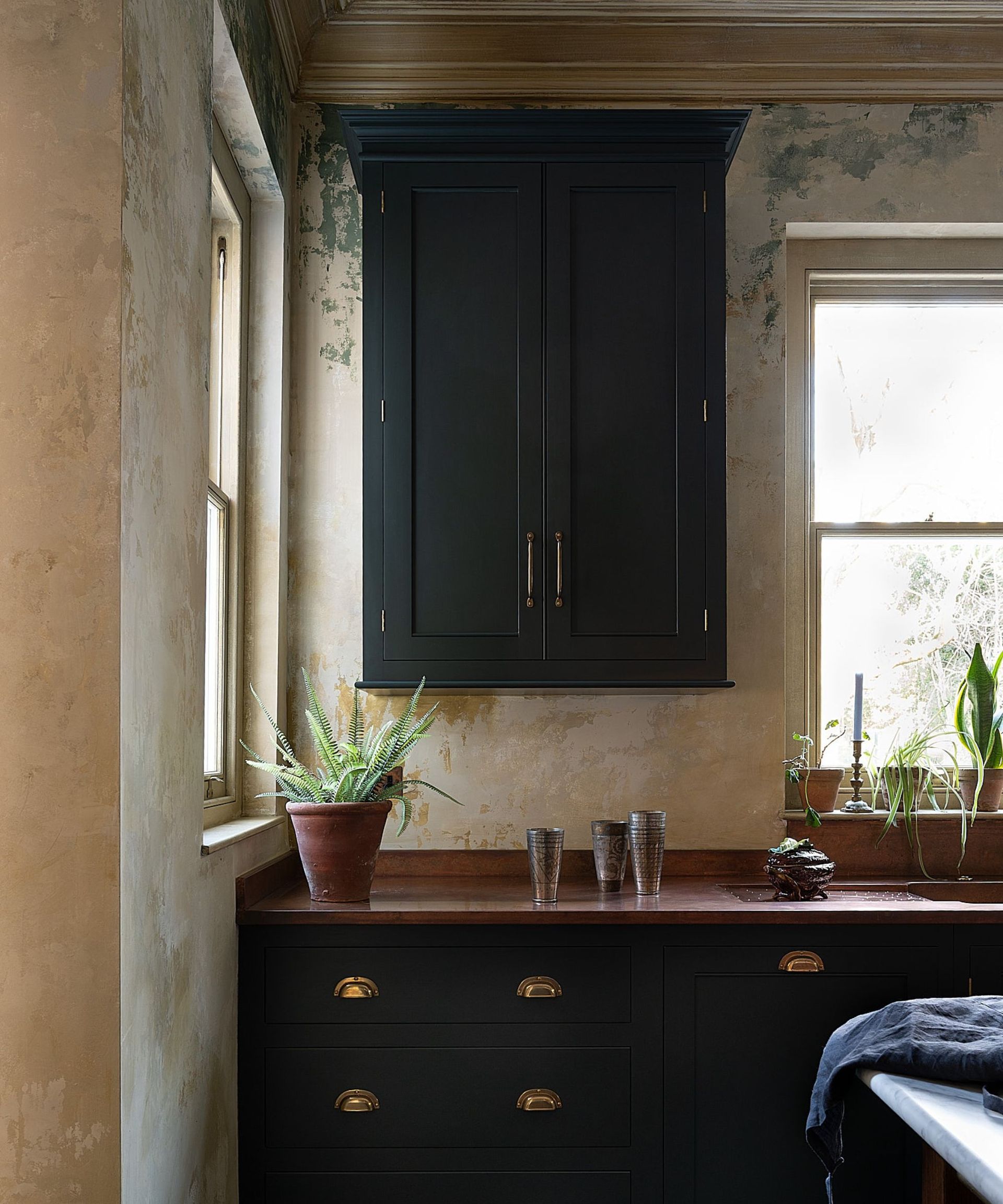 A kitchen with dark green cabinets and copper countertops