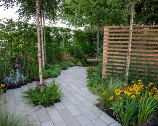 pale porcelain paving used for a patio and path with a slatted fence for garden screening