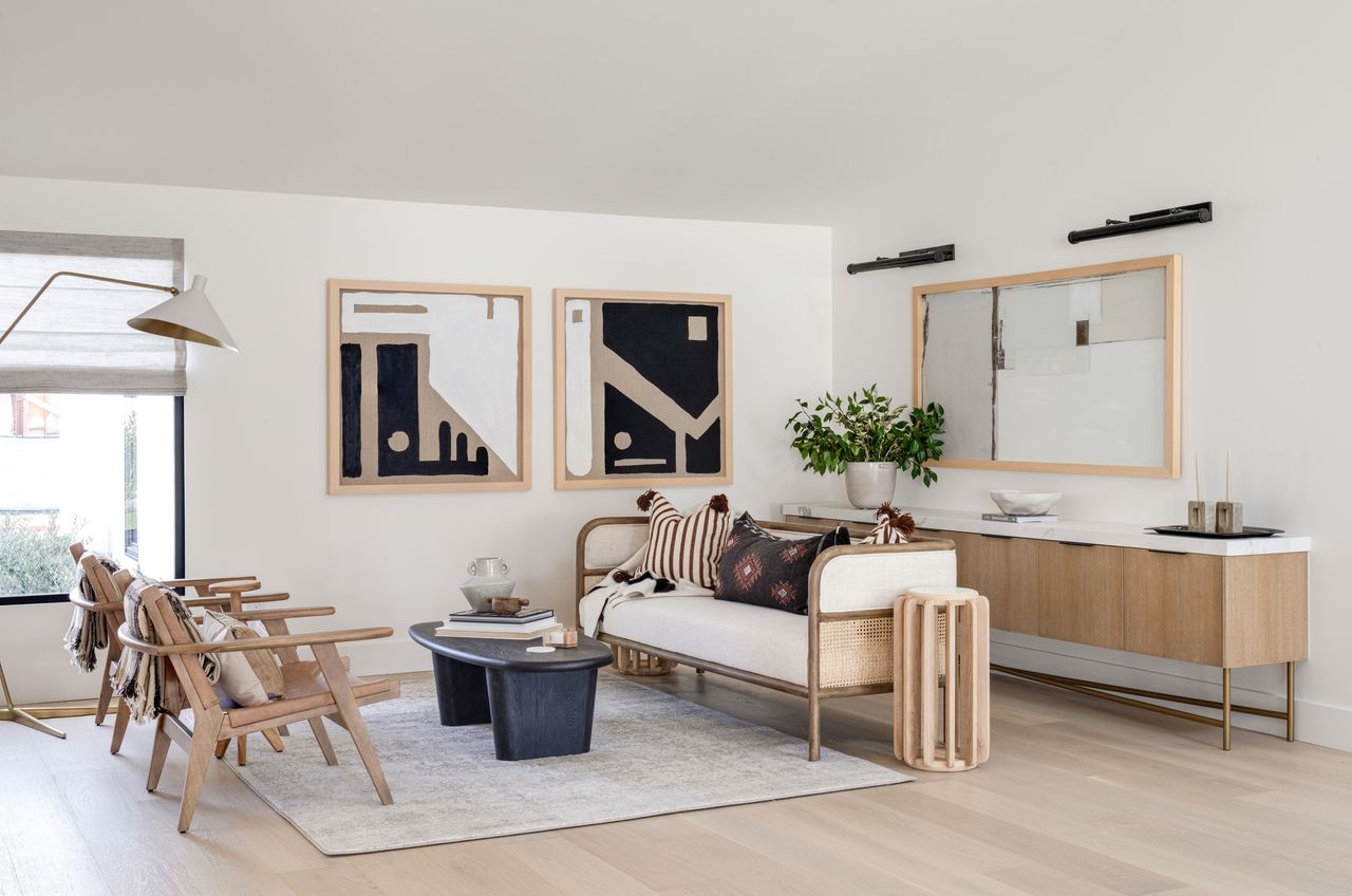 white living room with boho style decor, artwork, mirror, sideboard, couch and armchairs, black coffee table, floor lamp, rug