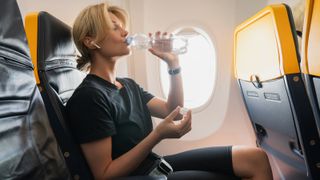 Woman drinking from water bottle on airplane