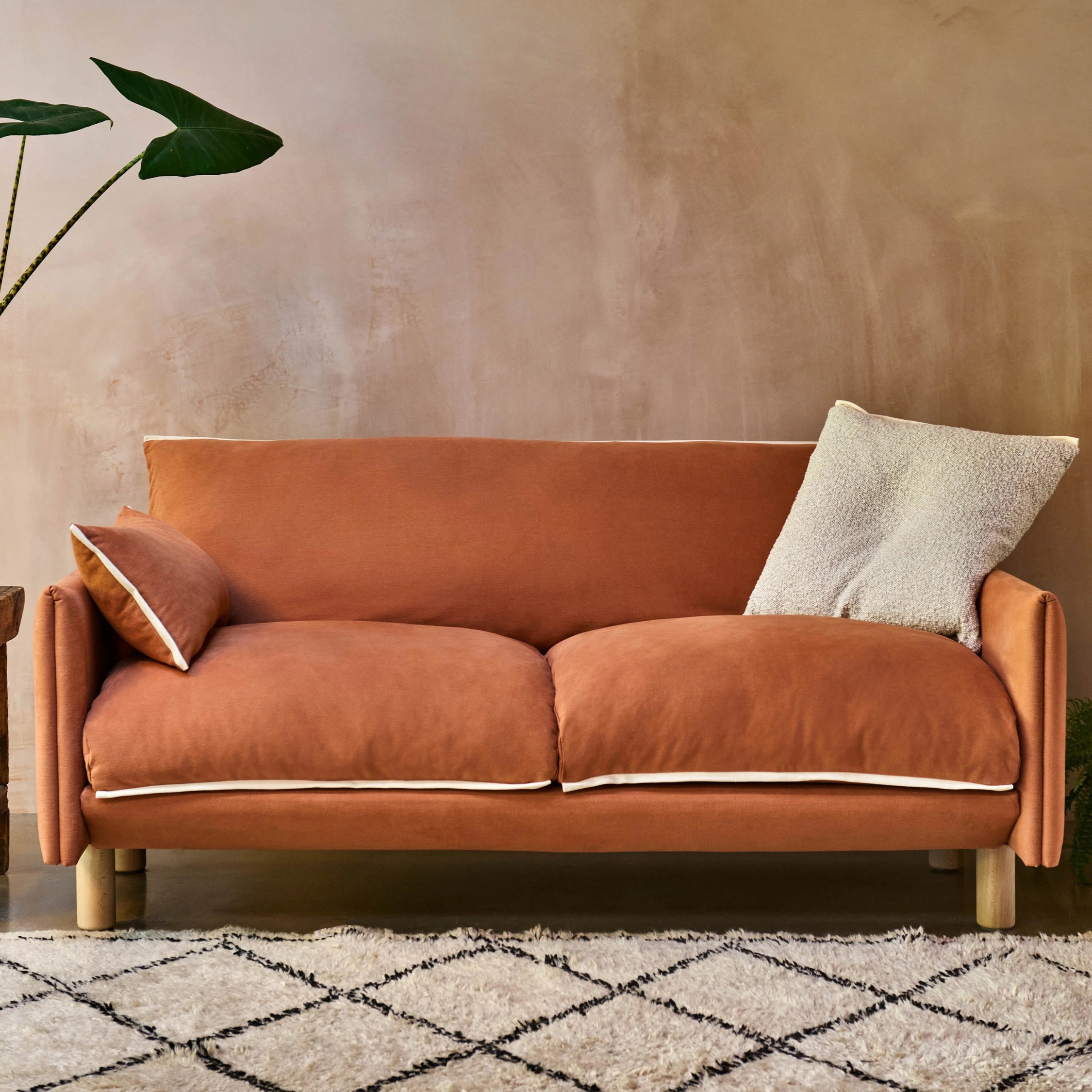 a terracotta color sofa against a plaster wall