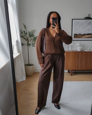 @femmeblk trägt braune Hosen und Strickjacke mit flachen Schuhen