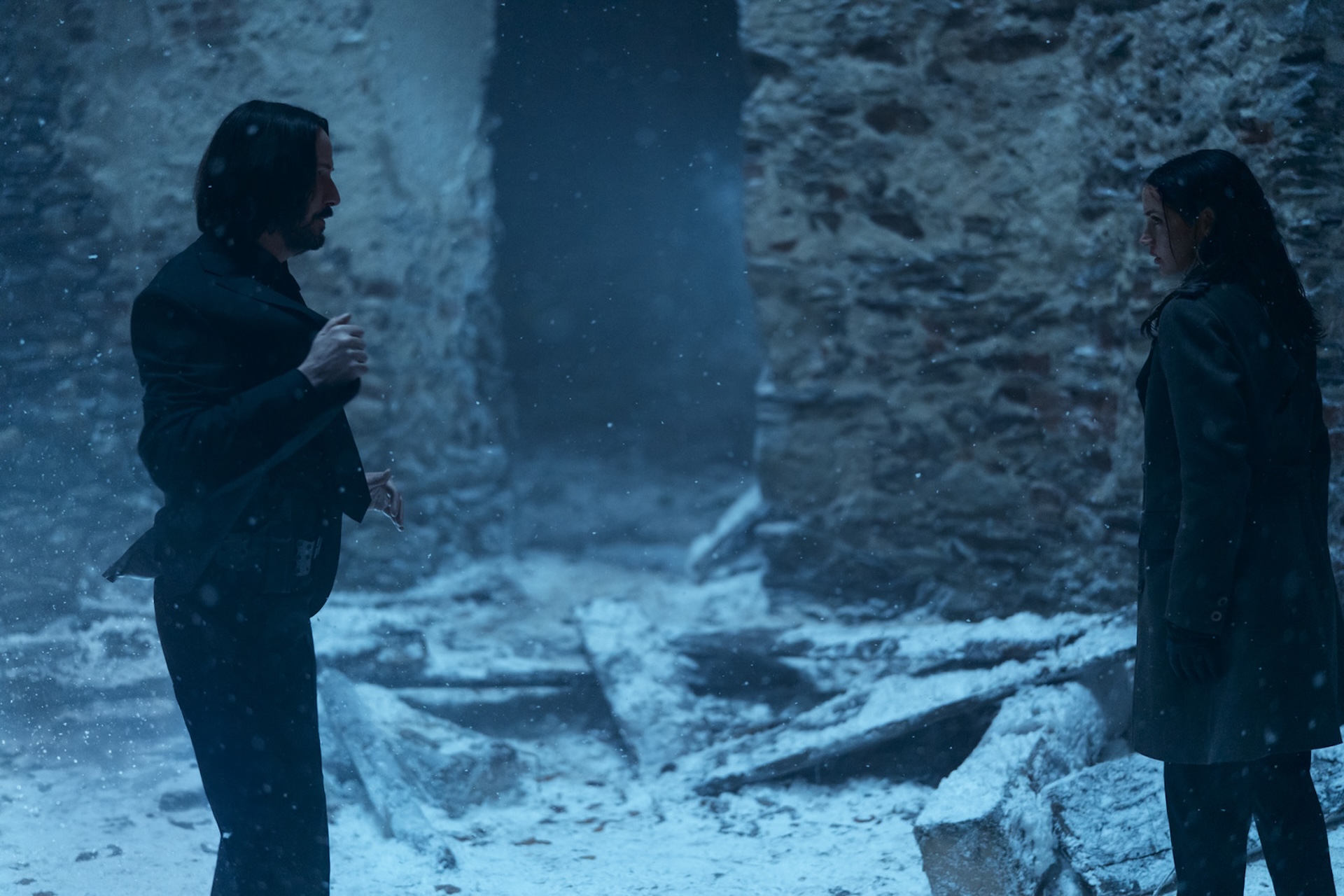 Keanu Reeves standing opposite Ana de Armas in the snow in Ballerina